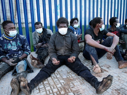 مهاجرون يجلسون خارج مركز المهاجرين المؤقتين عند عبور السياج في جيب مليلية بشمال إفريقيا، 19 يناير 2021 - REUTERS