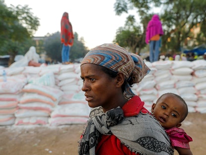 إثيوبية تحمل طفلها في طابور للحصول على الطعام في مدرسة تحوّلت إلى مأوى مؤقت للنازحين في تيغراي، 15 مارس 2021 - REUTERS