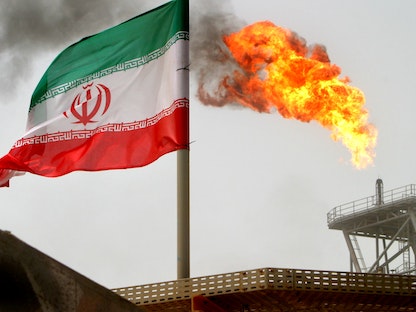 شعلة غاز على منصة لإنتاج النفط بجانب العلم الإيراني جنوبي إيران - 25 يوليو 2005 - REUTERS