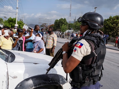 شرطي يحرس مدخل السفارة الأميركية في هايتي بينما يتجمع الناس لطلب اللجوء بعد اغتيال الرئيس جوفينيل مويس - 10 يوليو 2021 - REUTERS
