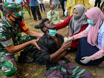عاملون في مجال الصحة يفحصون لاجئاً من الروهينجا بعد وصوله على متن قارب إلى مقاطعة آتشيه الإندونيسية. 25 ديسمبر 2022  - AFP