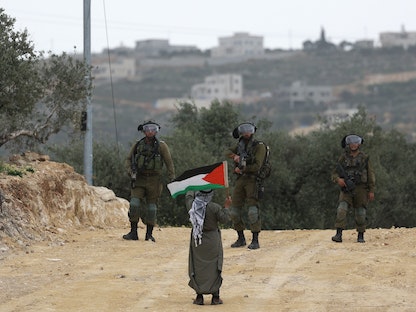 فلسطيني يواجه جنوداً إسرائيليين خلال مظاهرة في قرية بيتا جنوب نابلس بالضفة الغربية المحتلة احتجاجاً على مسيرة للمستوطنين إلى بؤرة استيطانية في موقع مجاور. 10 أبريل 2023 - AFP