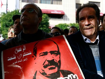 أشخاص يحملون صورة للسياسي التونسي الراحل شكري بلعيد في الذكرى الأولى لاغتياله في شارع الحبيب بورقيبة في تونس. 8 فبراير 2014 - Reuters