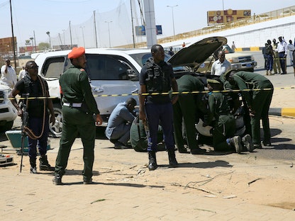 رجال أمن بالقرب من سيارة تضررت بعد انفجار استهدف موكب رئيس الوزراء السوداني عبد الله حمدوك، الخرطوم- 9 مارس 2020. - REUTERS