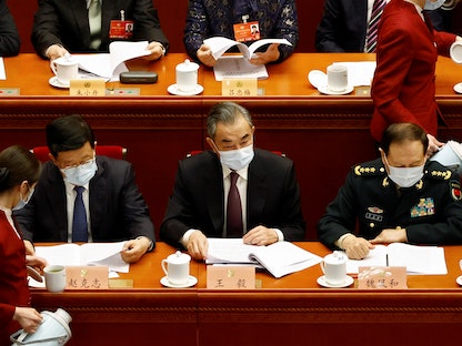 وزير الخارجية الصيني وانج يي يتوسط وزير الدفاع وي فنجي، ووزير الأمن العام تشاو كيجي في مقر البرلمان ببكين - 4 مارس 2022 - REUTERS