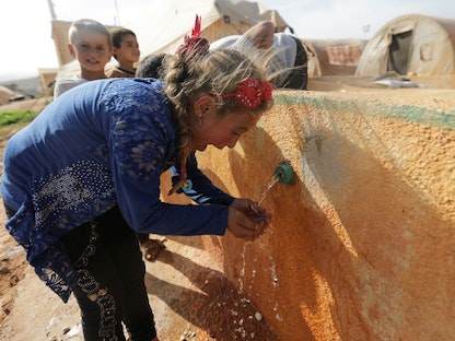 فتاة نازحة تشرب الماء في مخيم تيه بشمال إدلب في سوريا. 5 مايو 2021 - REUTERS