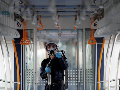 عامل يرش مواداً كيميائية للحماية من الفيروسات والبكتيريا داخل عربة قطار أنفاق في طوكيو. 9 يوليو 2020 - REUTERS