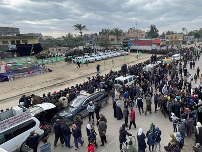 فلسطينيون ومقاتلون من كتائب القسام خلال إجراءات تسليم الدفعة الخامسة من المحتجزين الإسرائيليين إلى اللجنة الدولية للصليب الأحمر ضمن اتفاق غزة، دير البلح وسط قطاع غزة. 8 فبراير 2025 - Reuters