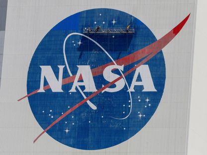عمال ينظفون شعار "ناسا" على مبنى تجميع المركبات قبل أن ترسل "سبيس إكس" اثنين من رواد الفضاء من ناسا إلى محطة الفضاء الدولية على متن صاروخها فالكون 9، في مركز كينيدي للفضاء في كيب كانافيرال، فلوريدا، الولايات المتحدة. 19 مايو 2020. - REUTERS