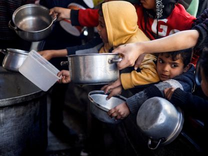 أطفال فلسطينيون ينتظرون الحصول على الطعام في مطبخ خيري وسط نقص الإمدادات الغذائية في رفح جنوب قطاع غزة- 5 مارس 2024 - Reuters