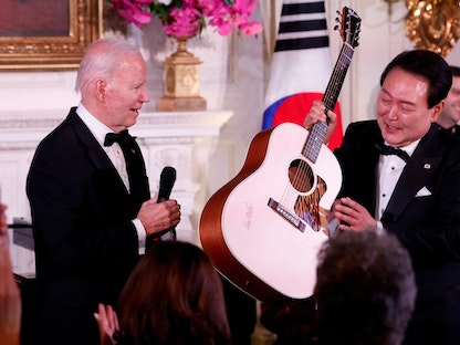 الرئيس الأميريكي جو بايدن يقدم جيتاراً وقعه الفنان دون ماكلين إلى رئيس كوريا الجنوبية يون سوك يول في حفل عشاء رسمي بالبيت الأبيض، واشنطن، الولايات المتحدة، 26 أبريل 2023. - REUTERS