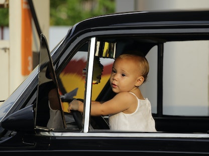 طفل يلعب خلف عجلة قيادة سيارة في محطة وقود في هافانا، 11 مايو 2012 - REUTERS