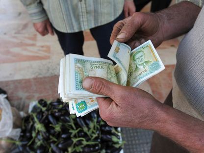 يعد نقوداً ورقية من فئة الليرة السورية - REUTERS