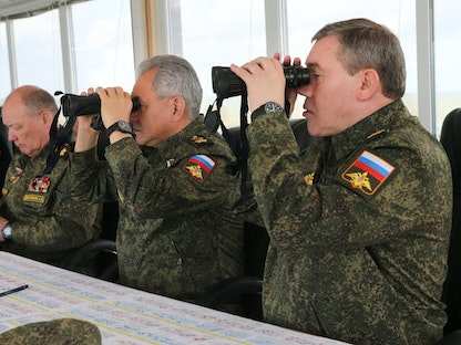 وزير الدفاع الروسي سيرجي شويغو (في الوسط) ورئيس الأركان العامة الروسية فاليري جيراسيموف (يميناً) وقادة عسكريون يشاهدون تدريبات عسكرية، شرق شبه جزيرة القرم - 22 أبريل 2021  - AFP