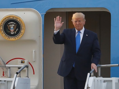 الرئيس الأميركي السابق دونالد ترمب يلوح وهو يقف على باب طائرة الرئاسة "إير فورس وان" - REUTERS