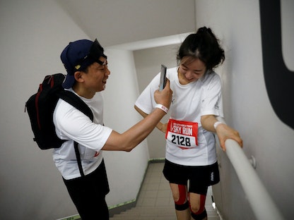 شاب يصور صديقته خلال ماراثون رأسي لصعود برج في سول بكوريا الجنوبية. 22 أبريل 2023 - REUTERS