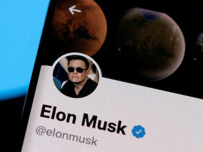 صورة تعبيرية لحساب إيلون ماسك على هاتف ذكي وفي الخلفية شعار تويتر - REUTERS