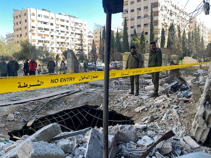 ضباط شرطة سوريون يقفون وسط أنقاض مبنى تعرض للتدمير في هجوم صاروخي على حي كفرسوسة وسط دمشق. 19 فبراير 2023 - REUTERS