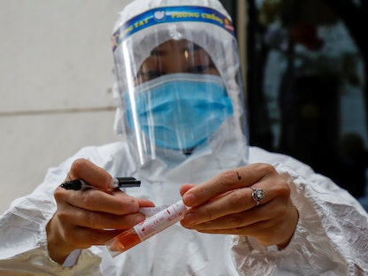 عامل صحي يرتدي بدلة واقية يضع علامة على أنبوب عينة في فيتنام - REUTERS