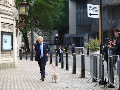 رئيس الوزراء البريطاني بوريس جونسون يصل مع كلبه إلى مركز الاقتراع  في لندن للتصويت في الانتخابات المحلية-  5 مايو 2022 - REUTERS