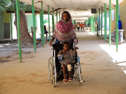 سيدة تنقل حفيدتها إلى مركز للعلاج بمنطقة عفار بعد إصابتها خلال معارك بين الحكومة ومتمردين في تيجراي، إثيوبيا - 24 فبراير 2022. - REUTERS