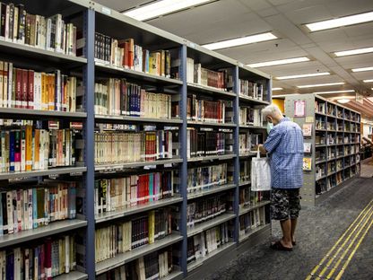 رجل ينظر إلى الكتب الموجودة في مكتبة عامة بهونغ كونغ - AFP