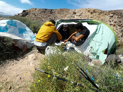 مهاجرون غير شرعيين يتناولون الطعام داخل خيمة في جبال جزيرة غران كناريا الإسبانية- 5 مارس 2021 - REUTERS