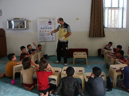 أحد أفراد الدفاع المدني السوري "الخوذ البيضاء" يعمل على توعية الأطفال بشأن مرض الكوليرا. 21 يوليو 2023 - twitter/SyriaCivilDefe
