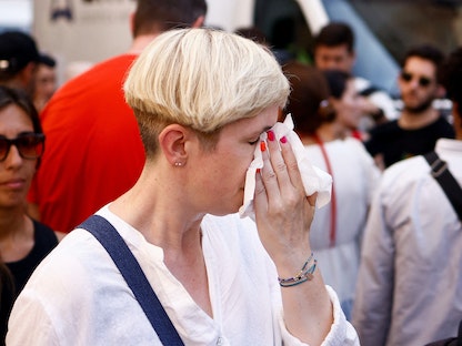سيدة تمسح العرق المتصبب على وجهها بمدنيل ورقي في روما بإيطاليا. 19 يوليو 2023 - REUTERS