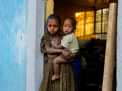 فتاة عمرها 11 عاماً تحمل شقيقها البالغ عاماً واحداً في مدرسة تحولت إلى مأوى مؤقت للنازحين في إقليم تيغراي، 15 مارس 2021 - REUTERS