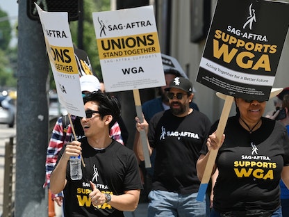 يسير كتّاب هوليوود ومؤيدوهم من نقابة ممثلي الشاشة SAG في اعتصام خارج استوديوهات وارنر بروس في بوربانك، كاليفورنيا، الولايات المتحدة، 30 يونيو 2023. - AFP