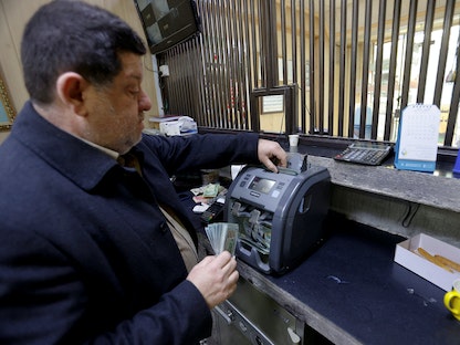مصرفي يعد الدولارات في محل للصرافة في العاصمة بغداد. 23 يناير 2023 - REUTERS