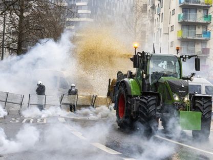 مزارع يستخدم جراره في مواجهة شرطة مكافحة الشغب البلجيكية خلال احتجاج دعت إليه منظمات المزارعين في بروكسل. 26 فبراير 2024 - AFP