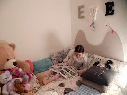 طفلة تقرأ مجلة قبل النوم في العاصمة البريطانية لندن. 17 مارس 2020 - REUTERS