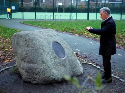 رجل صورة للوحة على حجر كُتب عليها (حديقة هرتسوج) تخليداً لذكرى حاييم هرتسوج، سادس رئيس لإسرائيل، المولود في بلفاست، وذلك في وقت أعدّ فيه مجلس مدينة دبلن مقترحاً لإعادة تسمية الحديقة  إلى "حديقة هند رجّب" نسبةً إلى الطفلة الفلسطينية التي قتلتها إسرائيل هند رجّب من غزة، في دبلن، إيرلندا. 30 نوفمبر 2025 - Reuters