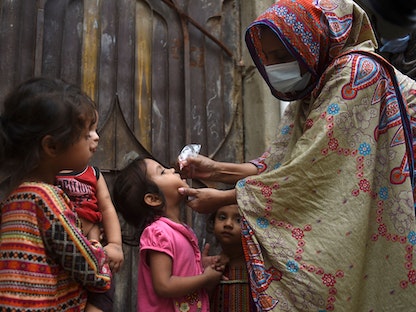 عاملة في القطاع الصحي تطعم أطفالاً باللقاح المضاد لشلل الأطفال في مدينة كراتشي الباكستانية. 15 أغسطس 2022 - AFP