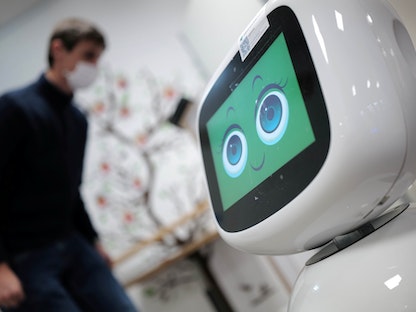 روبوت في ألمانيا يفحص درجة حرارة شاب خلال انتشار فيروس كورونا  - REUTERS