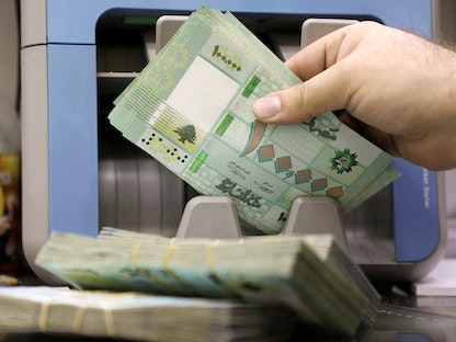  رجل يعد أوراقاً نقدية بالليرة اللبنانية في متجر لصرافة العملات في بيروت - 5 يناير 2022 - REUTERS