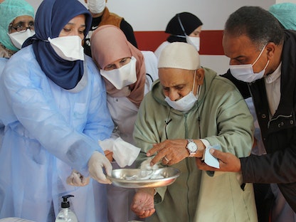  عمال الرعاية الصحية يساعدون رجلاً مسناً بعد تلقيه لقاح كورونا خلال حملة التطعيم الوطنية في سلا، المغرب، 29 يناير 2021 - REUTERS
