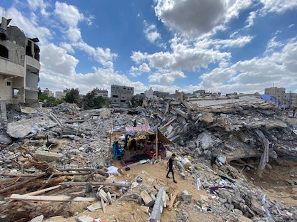 طفل فلسطيني يسير بالقرب من أنقاض منزله الذي دمرته الغارات الإسرائيلية في غزة -23 مايو 2021 - REUTERS