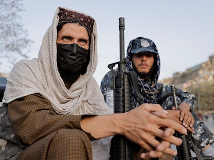 عنصران مسلحان من "طالبان" يجلسان عند نقطة تفتيش بعد الانفجار الذي استهدف مجلس عزاء والدة أحد قياديي الحركة في كابول- 3 أكتوبر 2021 - REUTERS