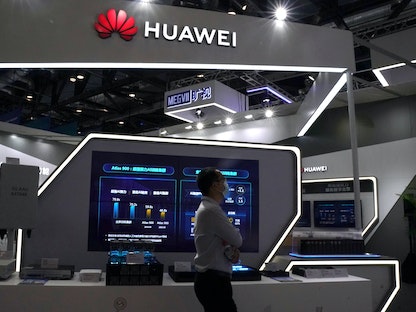 رجل يرتدي قناعاً للوجه يمر بجوار جناح لشركة Huawei في معرض الصين الدولي للتجارة في الخدمات (CIFTIS) لعام 2020 في بكين - REUTERS