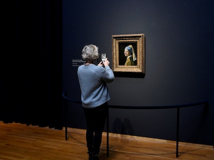 سيدة تنظر إلى لوحة رسمها الفنان الهولندي يوهانس فيرمير بعنوان "الفتاة ذات القرط اللؤلؤي" في متحف ريجكس بأمستردام  - AFP