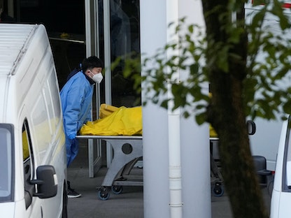 عامل يدفع عربة تحمل حقيبة جثث في أحد المدافن مع استمرار تفشي مرض فيروس كورونا (COVID-19) في شنغهاي ، الصين- 4 يناير 2023. - REUTERS