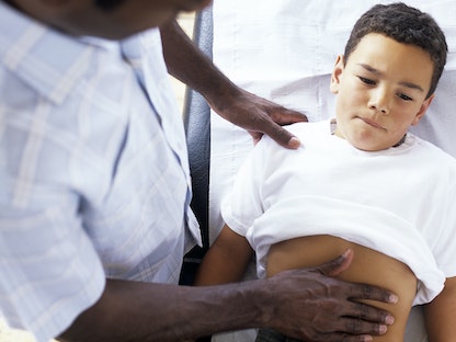 طبيب عام يفحص طفل يبلغ يعاني من آلام البطن. 28 أبريل 2005 - AFP