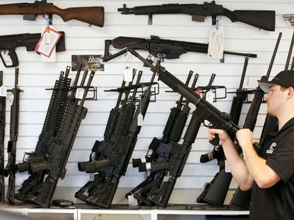 بائع في متجر أسلحة أميركي خلال فحص بندقية من طراز AR-15  - REUTERS
