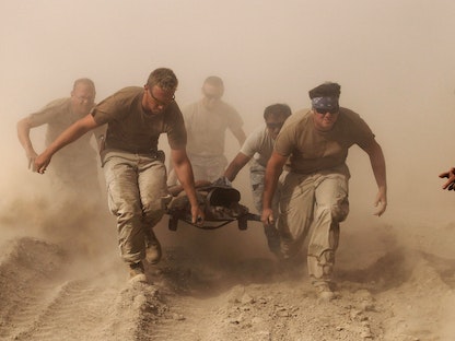 عناصر من البحرية الأميركية يحملون جريحاً أصيب في انفجار طائرة هليكوبتر طبية في ولاية قندهار، أفغانستان. 2 أكتوبر 2010 - REUTERS