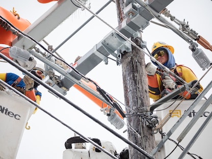 عاملان يصلحان خطاً كهربائياً في أوستن بولاية تكساس، 18 فبراير 2021 - Bloomberg