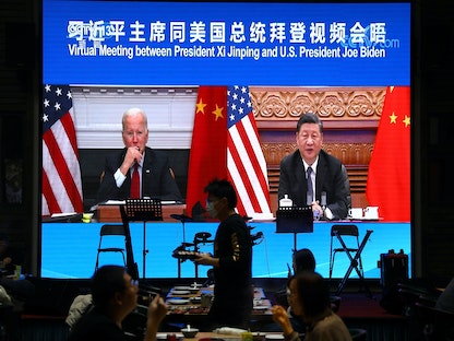 الرئيسان، الصيني شي جين بينج والأميركي جو بايدن، على شاشة في مطعم ببكين خلال اجتماعهما الافتراضي - 16 نوفمبر 2021 - REUTERS