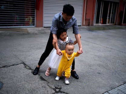 مواطن صيني يلعب مع طفليه في ضواحي شنغهاي - 3 يونيو 2021 - REUTERS
